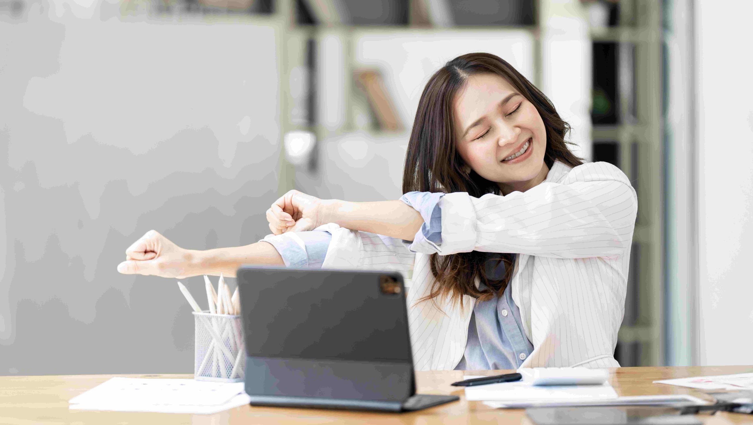 Mujer en oficina estirándose durante una pausa laboral, representando el bienestar y la desconexión en el trabajo